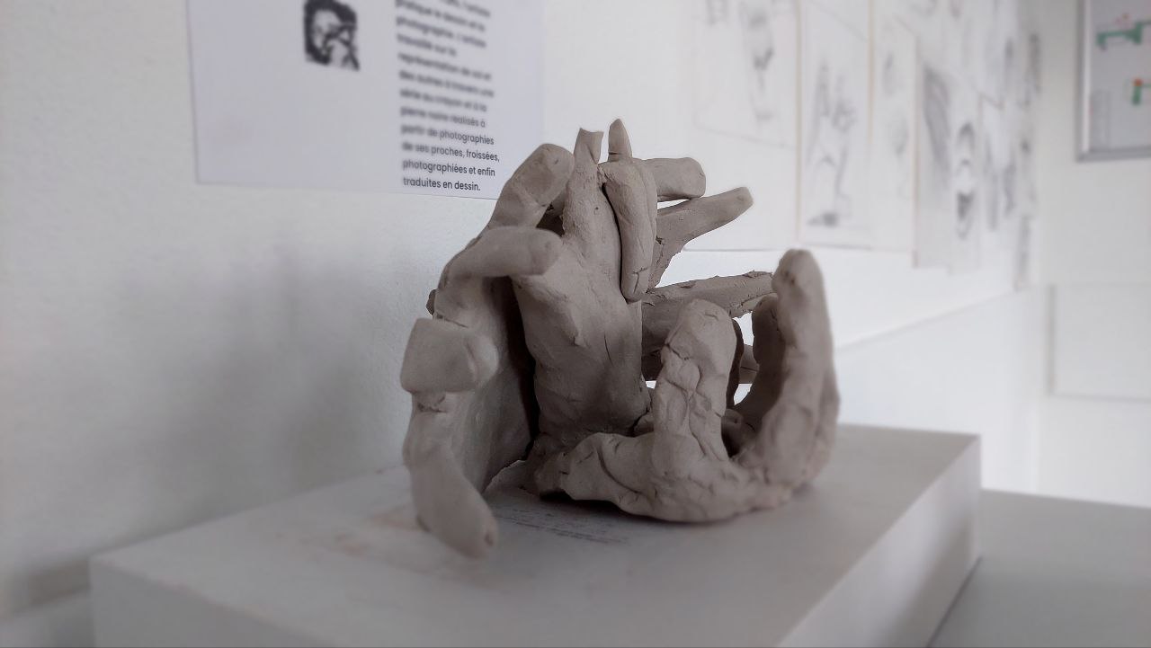 des sculptures de mains en terre qui s'entrecroisent